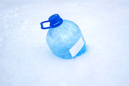 a plastic canister for car windows lies in the snow. Glass-washing liquid.