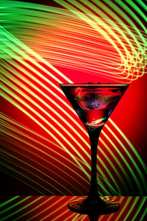 A glass of chilled martini on a red background, with green backlight.の写真素材