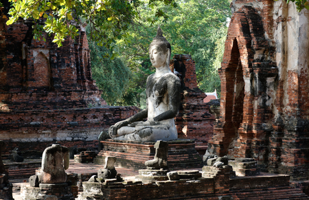 The buddha statue in meditation posture with the sunlight emitting from the sky to illustrate a look of wise, calm, discreetly and respectful of his enlightenment. Horizontal sight.の写真素材
