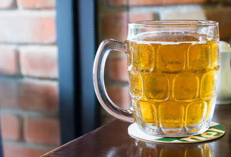 A beautiful pint glass of beer on wooden table.の写真素材