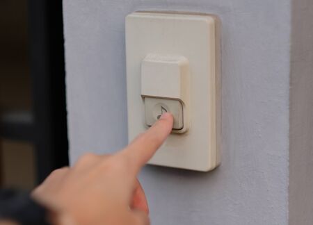 Focus on finger pressed on the doorbell.