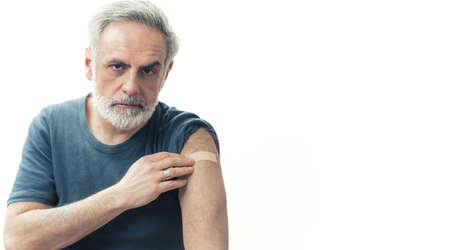 Middle-aged man showing the arm patch after the vaccination - immunization concept. High quality photoの写真素材