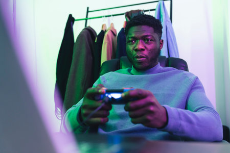 Focused afroamerican man playing video game joystic - medium shot. High quality photo