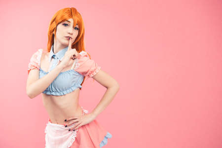 Silence Secret gesturing and posing European cosplay woman copy space pink background. High quality...