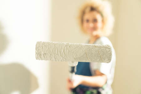 Paint roller beeing held next to the camera by crafty woman. High quality photo