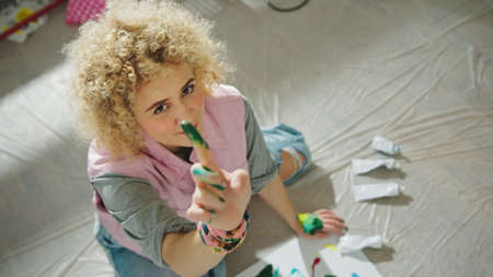Inspired woman has fun painting with tempera and hands. Shot from above. High quality photoの写真素材