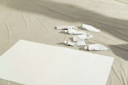 tempera acrylic paint tubes scattered around on the painting table next to the paper canvas. High quality photoの写真素材