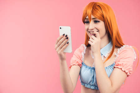 European Ginger-haired Teenager Checking Out Her Social Media, Followers, Likes And Biting Her Nails With Excitement studio shot. High quality photoの写真素材