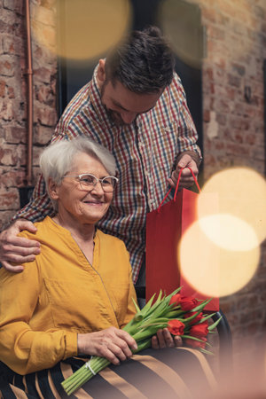 beautiful scene between elderly mother and her grown-up son giving her a surprise gift on Mothers Day. High quality photoの写真素材