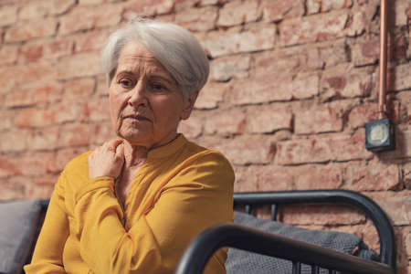 lonely depressed grandma sitting alone on a sofa. High quality photoの写真素材