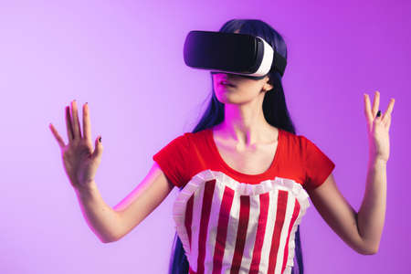 European model with long hair and vr glasses is rising her hands medium studio shot magenta background. High quality photoの写真素材