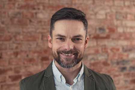 well-dressed middle-aged male entrepreneur medium close up shot brick wall background. High quality photoの写真素材