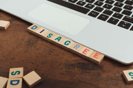 Disagree word written on wooden letter cubes tiles - computer desk and keyboard. High quality photoの写真素材