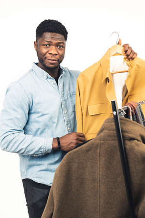 black man showing yellow jacket coat rack white background - portrait shot. High quality photoの写真素材