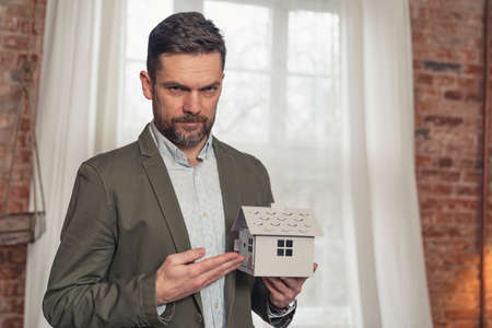 serious caucasian middle-aged architects advertisement presenting white house artificial model . High quality photoの写真素材