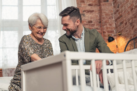 relatives soon-to-be grandmother and soon-to-be father are happy after buying a solid crib for a future baby. High quality photoの写真素材