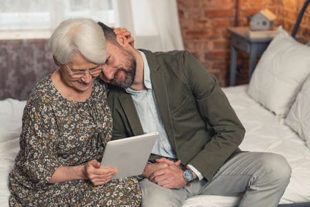 caucasian grandmother got her new technological gadget from her middle-aged son on Grandparents Day. High quality photoの写真素材