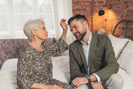 elderly retired caucasian lady petting her sons brown hair celebrating Mothers Day. High quality photoの写真素材