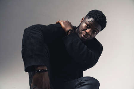 stressed person of color touching his shoulder seated white background - medium shot. High-quality photoの写真素材