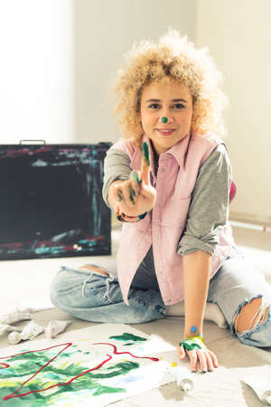 Female Artist Smiles Putting Colors On Her Face Using Fingers. High quality photoの写真素材