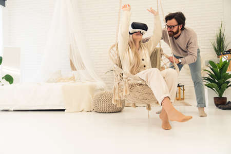 VR learning, middle-aged husband shows his beautiful wife the new VR set while spinning her on a swing. High quality photoの写真素材