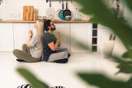 back to back meditation lotus practiced by long-haired caucasian woman and her boyfriend in their shared flat. High quality photoの写真素材