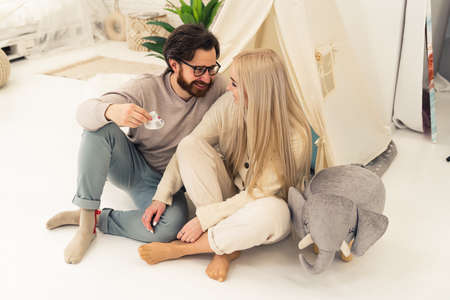soon-to-be parents in their late 20s sitting in a babys room, holding little infant shoe, and talking about the future. High quality photoの写真素材