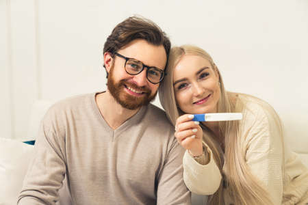 caucasian heterosexual couple happily showing pregnancy test to the camera. High quality photoの写真素材