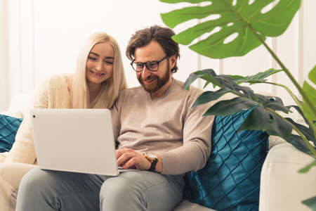 caucasian spouses energetically shopping online and watching funny videos in the internet. High quality photoの写真素材