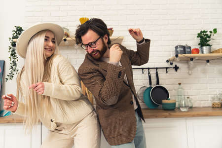 young European husband dancing with his beautiful long-haired wife in the kitchen celebrating their anniversary. High quality photoの写真素材