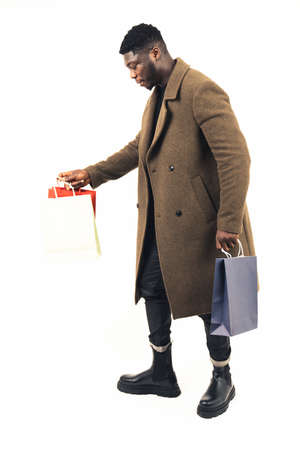 black guy holding a lot of bags white background - full shot. High-quality photoの写真素材