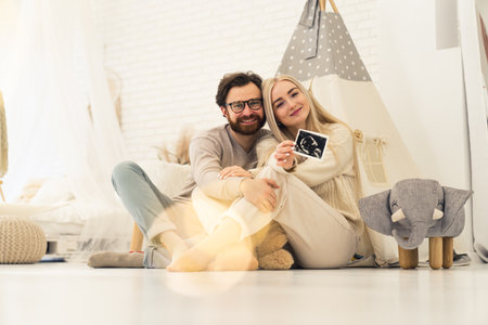 Beautiful caucasian couple smiling and showing sonography pictures of their baby. High quality photoの写真素材