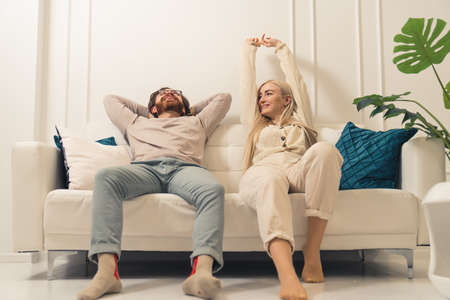 Happy millennial couple relaxing together on comfortable couch in their beautiful bright sitting room. High quality photoの写真素材