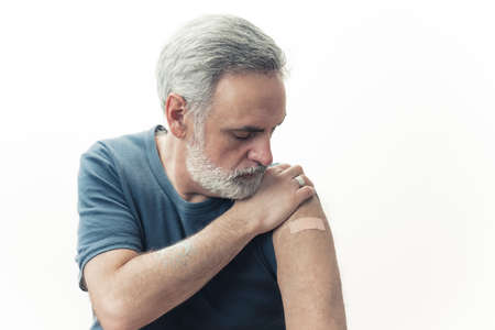 Middle-aged man looking at his vaccinated arm - influenza and coronavirus spread prevention. High quality photoの写真素材