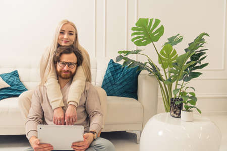 young caucasian couple looking at camera while cuddling and holding a laptop on mans knees. High quality photoの写真素材