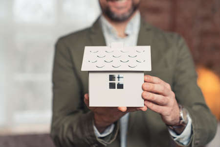young bearded architect in a suit holding a white home model real estate. High quality photoの写真素材