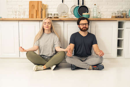 happy caucasian couple meditating on quarantine in their modern apartment, taking care of physical and mental health. High quality photoの写真素材