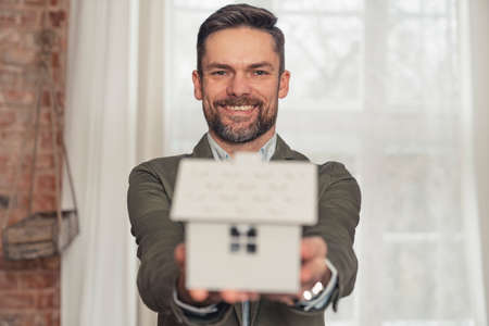 middle-aged caucasian businessman showing the house model and selling real estate. High quality photoの写真素材