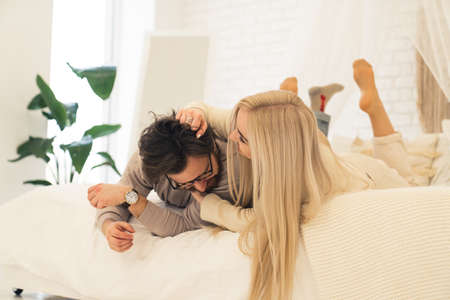 youthful married couple bonding and teasing on bed in their brand new apartment. High quality photoの写真素材
