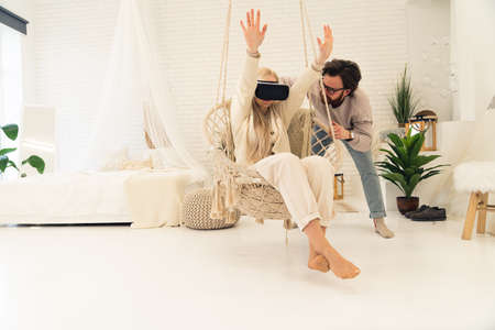 young caucasian woman beginning her adventures with virtual reality goggles with the help of her husband. High quality photoの写真素材