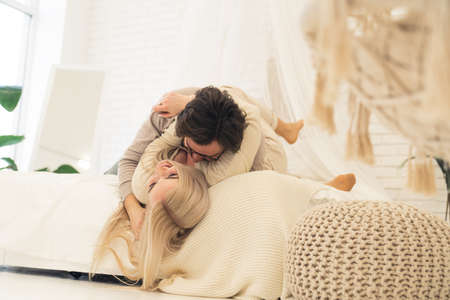 Loving caucasian young couple laying together in bed, cuddling, and laughing. High quality photoの写真素材