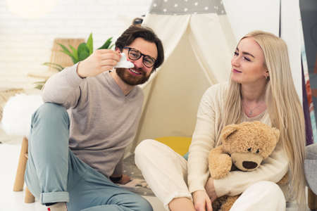 caucasian middle-aged entrepreneur is happy about becoming a father and talks to his beautiful fiancee while holding a small shoe. High quality photoの写真素材