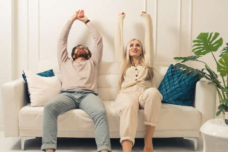 European millennial bearded man and his beautiful long-haired girlfriend happily enjoying lazy weekend in their modern apartment . High quality photoの写真素材