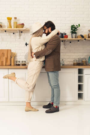 Vertical shot of a hug between two caucasian lovers, woman lifting her one leg up. High quality photoの写真素材