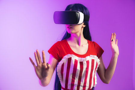 European model with long hair and vr glasses is rising her hands medium studio shot magenta background. High quality photoの写真素材