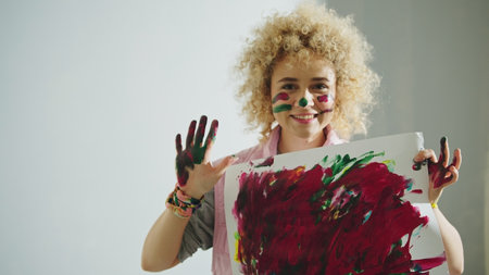 Happy caucasian girl with painted face showing her painting - artwork workshop. High quality photoの写真素材