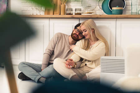 young caucasian couple sitting in the kitchen in their modern flat cuddling and thinking about the future. High quality photoの写真素材