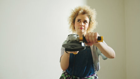Pensive girl holding angle disc grinder and thinking about new DIY Project. High quality photoの写真素材