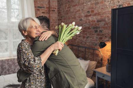 elderly caucasian woman wearing eyeglasses receives a hug from her middle-aged caucasian son. High quality photoの写真素材