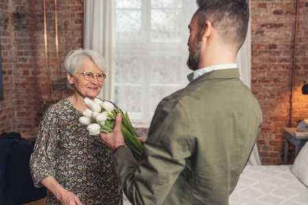 middle-aged caucasian man came home to surprise his mother with bouquet of flowers. High quality photoの写真素材